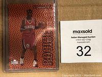 Front view of Iverson rookie card in protective sleeve alongside auction lot number sign