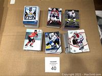 Top view of six large stacks of hockey trading cards on a cardboard surface. Cards show images of hockey players in full gear.