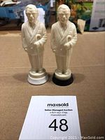 Pair of Colonial Saunders plastic salt and pepper shakers standing upright with a MaxSold label.