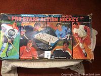 Top and side views of original game box showing colorful hockey player artwork including Gordie Howe and Phil Goyette with wear and tear visible