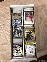 Two boxes containing stacks of assorted hockey cards, some with glossy and holographic finishes.