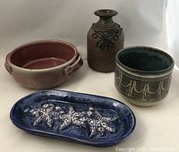 Set of four pottery pieces showing vase, starfish dish, handled dish and bowl on white background