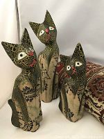 Three cracked finish folk art cats carved from wood, painted and decorated, shown standing together
