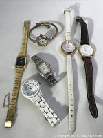Overview of all six ladies quartz watches laid out on white surface showing various styles, bands and dial colors.