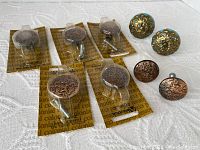 Seven vintage copper drawer knobs, six new in packaging, two teal ceramic knobs with brass accents, all displayed on white cloth.
