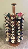 Full view of wooden thread spool caddy loaded with multiple pegs holding thread spools