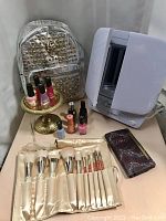 Full lot: makeup mirror, nail polishes on brass stand, silver leather wallet, makeup brushes laid out, vintage razor.