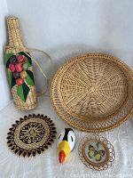 Full view of all five pieces including woven basket, woven bottle with fruit decor, wooden toucan, coaster, and butterfly frame.