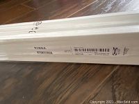 Photo of packaged white IKEA Ribba floating picture ledge showing product label, dimensions and barcode