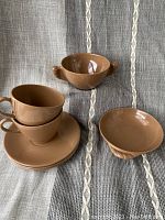 Vintage mid century Melmac tea set pieces arranged showing cups, saucers, and bowls with handles.