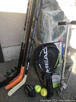 Photo showing hockey sticks, tennis racquet, balls, and Razor scooter