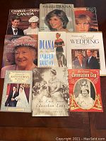 Collection of seventeen books about royal families and notable royal events or people, arranged on a wooden table. Titles include biographies and commemorative books about Princess Diana, Queen Mother, Charles and Diana's visit to Canada, and royal weddings.