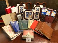 Overall view of various photo albums and picture frames arranged on table including binders and small decorative box.