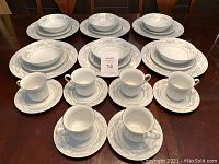 Full set of 6 plates, 6 bowls, 6 side plates, 6 cups, and 6 saucers arranged on a table.