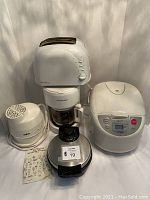 Photo showing the front view of the Salton ice cream maker, Proctor Silex coffee maker under a white Moulinex toaster, and the Tiger rice cooker closed with digital control panel visible.