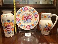 Front view of vase, pitcher, and decorative plate with measuring tape for scale
