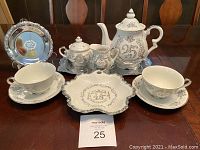 Full view of one complete 25th anniversary tea set including teapot, sugar bowl with lid, creamer, two cups and saucers, and decorative serving plate with '25' floral motif.