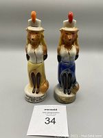 Front view of two Jim Beam collectible whiskey decanters shaped as fox ladies in western hats and attire, placed side by side on a gray background.
