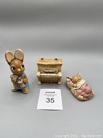 Front view of three Pendelfin figurines: a bunny playing flute, a piano, and a reclining cat with wings.