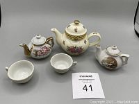 Photo showing entire tea set items arranged: 3 miniature tea pots and 2 small bowls