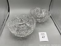 Photo showing two heavy crystal cut bowls with star and geometric cut patterns, scalloped edges, placed side by side.