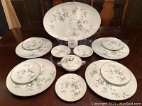 Photo of complete 14-piece Noritake Lorene china set displaying serving platter, dinner plates, dessert plates, sugar bowl with lid, and creamer with floral patterns and platinum trim.
