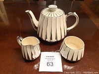 Full set consisting of teapot, creamer, and sugar bowl displayed on wooden table.