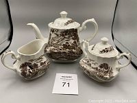 Vintage Ridgway Country Days tea set with tea pot, sugar bowl, and creamer, displayed against plain gray background. All pieces are white ceramic with brown countryside scenic transferware patterns.