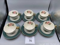 Top view of 6 cups and 6 saucers showing floral design and gold trim