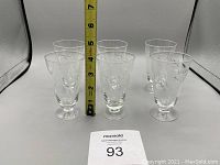 Six vintage pinwheel patterned glasses with measuring tape showing heights around 4.5 to 5 inches.