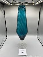 Front view of the tall bluish glass vase with swirling pattern on clear pedestal base.