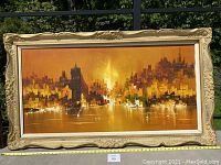 Front view of the large vintage cityscape painting in ornate carved wood gold-tone frame showing full artwork and size tape measure.