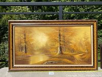 Front view of the large framed vintage oil painting of a forest landscape in autumn colors, showing overall condition and frame.