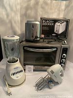 All four appliances pictured together: KitchenAid convection oven, Black & Decker toaster in box, Osterizer blender, Proctor Silex hand mixer