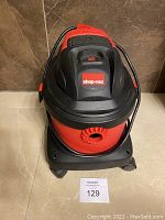 Front angled view of red and black Shop-Vac vacuum cleaner showing unit and attached power cord.