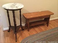 Wide view showing the wood bench and round marble-top side table side by side on wood floor.