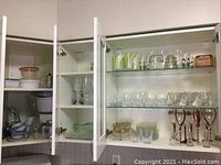 Glass cabinet with shelves containing various glassware, bowls, cups, plates, and pitchers.