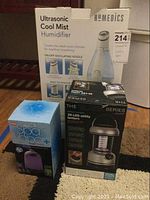 Photo of three original product boxes showing the Homedics Ultrasonic Cool Mist Humidifier, Shift Black Series 20-LED utility lantern, and Spa Vapor diffuser