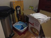 Wide view of lot showing pressure cooker box, electric griddle box, blue freezer packs in white tub, and Veggetti box.