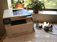 Photo of HP printer and Panasonic phones on countertop with plants in background