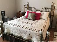 Full view of queen-size brass bed frame with quilt and pillows in bedroom