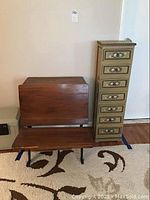 Front view of school desk and tall chest of drawers side by side against a wall with carpeted floor.