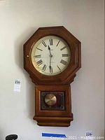 Full view of the Verichron Winchester wall clock showing the oak wood case with octagonal dial and pendulum window.