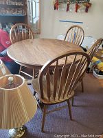 Full view of round wooden dining table with four matching spindle back chairs.