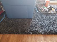 Close-up side view of thick black and grey shag rug showing dense pile and texture laid on hardwood floor.