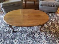 Front view showing oval wooden table top with medium finish and traditional cabriole legs.