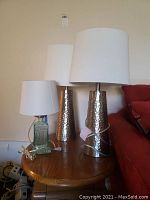 Wide view of all three lamps on wooden table against wall.