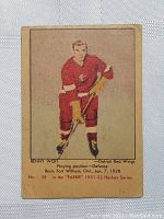 View of vintage 1951 Parkhurst Benny Woit rookie card front side showing the player in red Detroit Red Wings uniform standing with hockey stick.