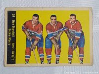 Front of the hockey card showing three players in red Montreal Canadiens jerseys with yellow background, some creases visible.
