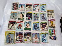 Photo showing part of the lot with multiple 1976 NHL O-Pee-Chee hockey cards including Ron Carter, Tim Young, Clark Gillies, Larry Giroux, Ron Greschner, Errol Thompson, and Bob Gassoff.